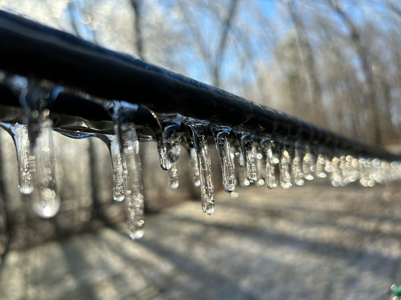 a line of water droplets hanging from a metal rail